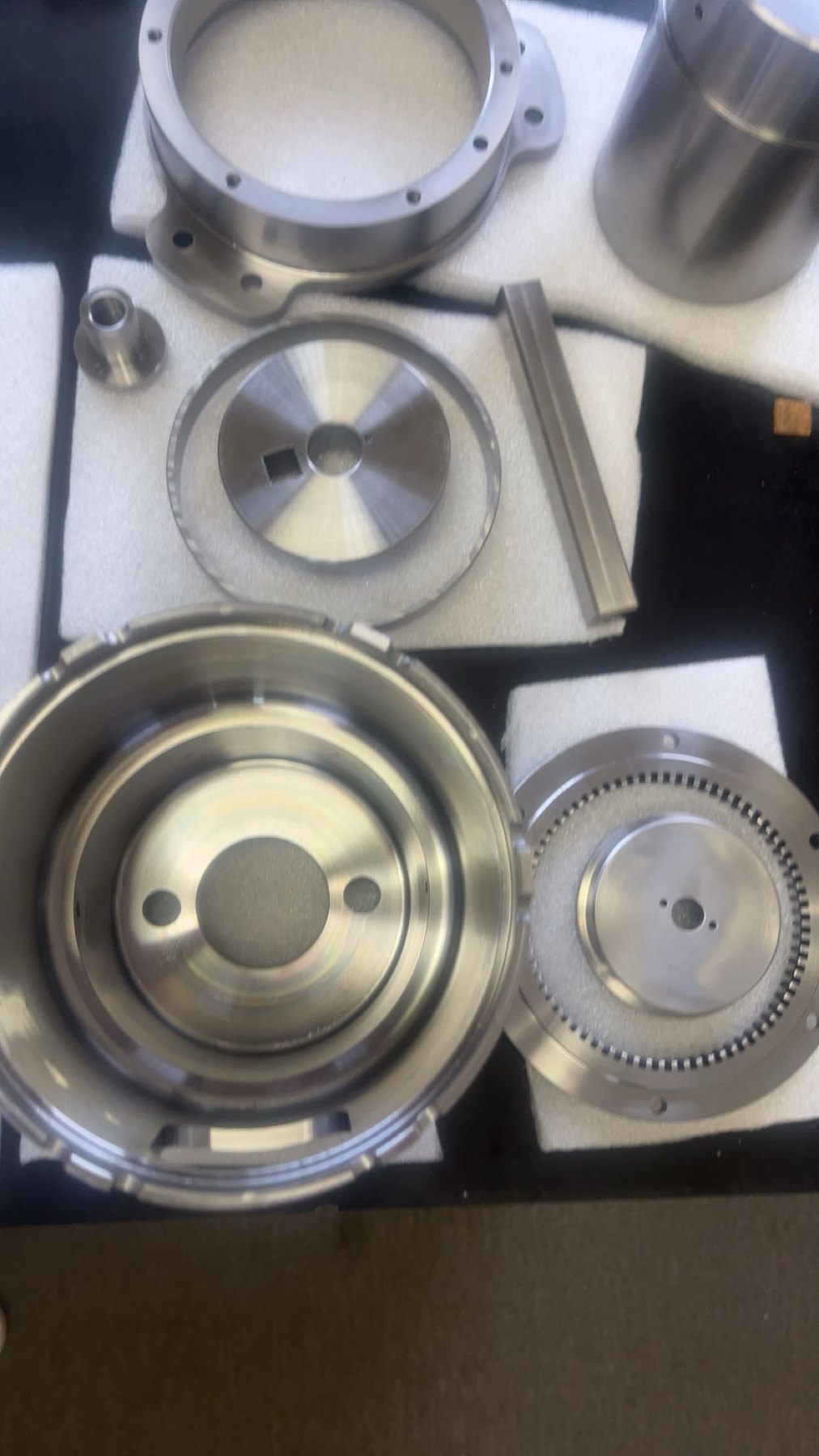 Precision CNC machined metal housings, rings, and plates on shop foam